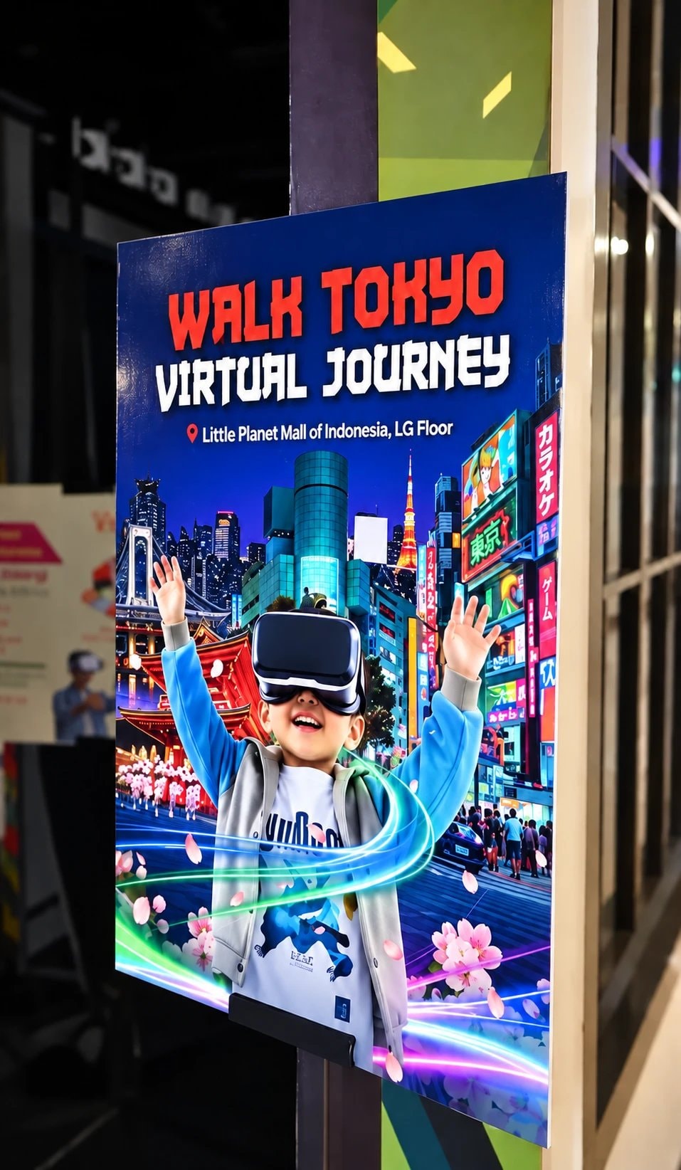 Signage Walk Tokyo Virtual Journey terpasang di tiang area event, bertuliskan lokasi Little Planet Mall of Indonesia LG Floor, dengan visual anak memakai headset VR di tengah Tokyo Tower, Rainbow Bridge, kuil, jalanan neon, dan bunga sakura