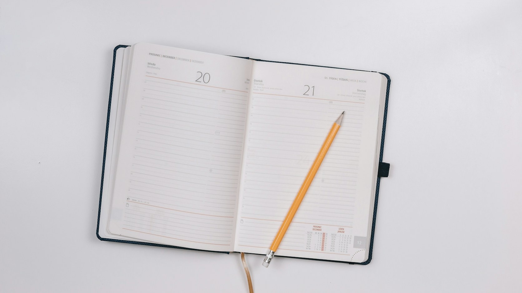 Buku agenda terbuka dengan pensil di atasnya