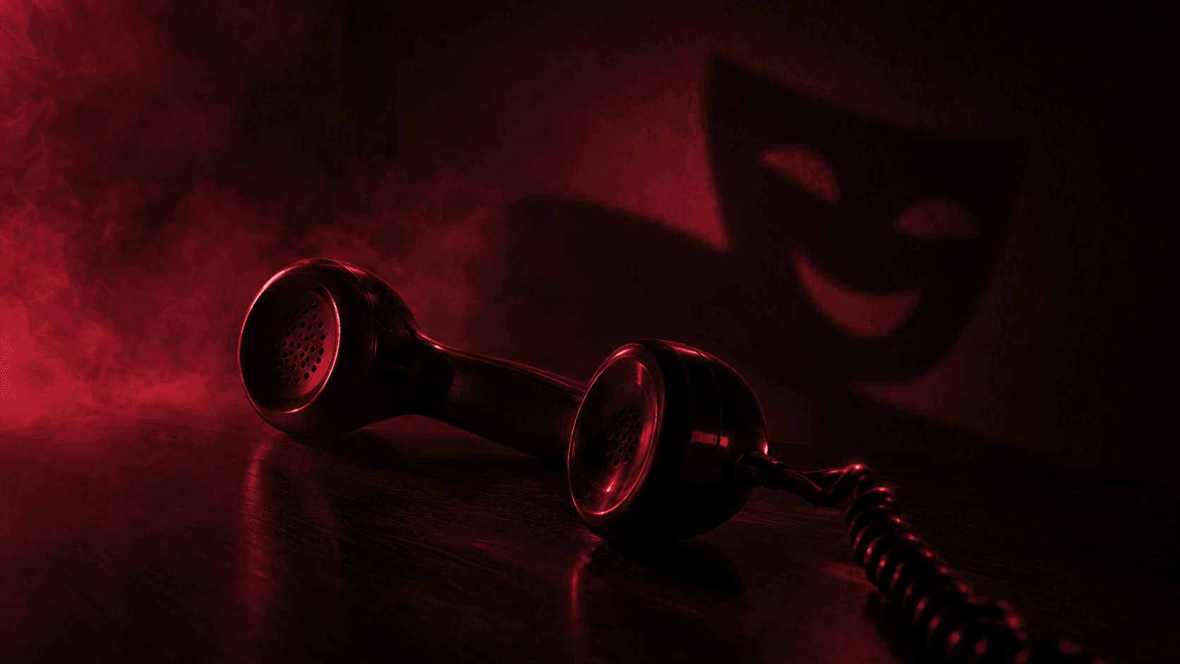 Gagang telepon klasik tergeletak di meja gelap, bayangannya di dinding berbentuk topeng teater yang tersenyum