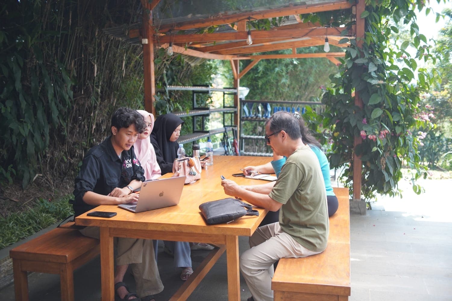 Prasetyo bekerja bareng klien di meja kayu di taman